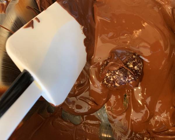 date ball being coated with the melted chocolate