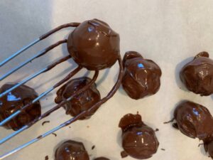 date balls dipped in chocolate being transferred to baking sheet